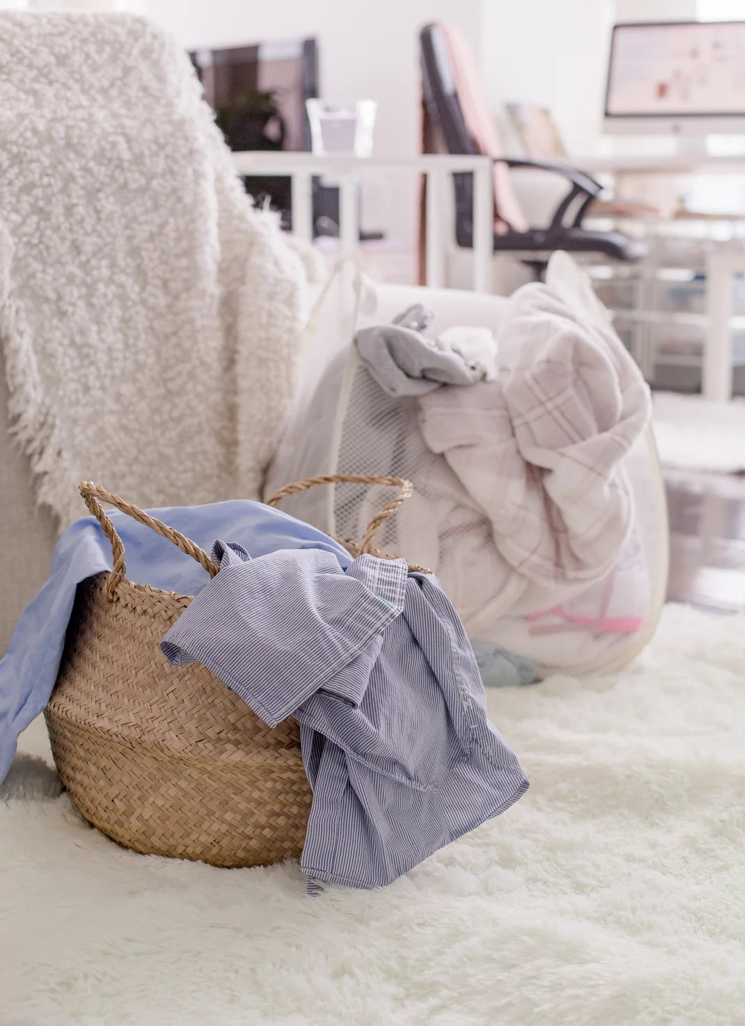 Wicker basket with clothes on a white surface in a room setting